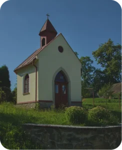 Malá bílá kaplička s věžičkou uprostřed zeleně